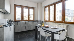 Cocina moderna con comedor, ventanas amplias y vista a edificios.
