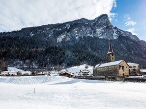 Un pueblo cubierto de nieve, con una iglesia y una montaña al fondo.
