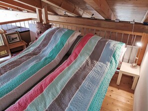 Una habitación acogedora con techo de madera y cama con ropa de cama a rayas.