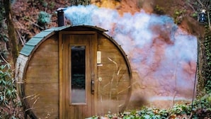 A wooden cabin with a chimney emitting smoke, surrounded by forest. -   Rustic Wilderness Cabin Retreat Private Forest Getaway in East Tennessee (Newport)