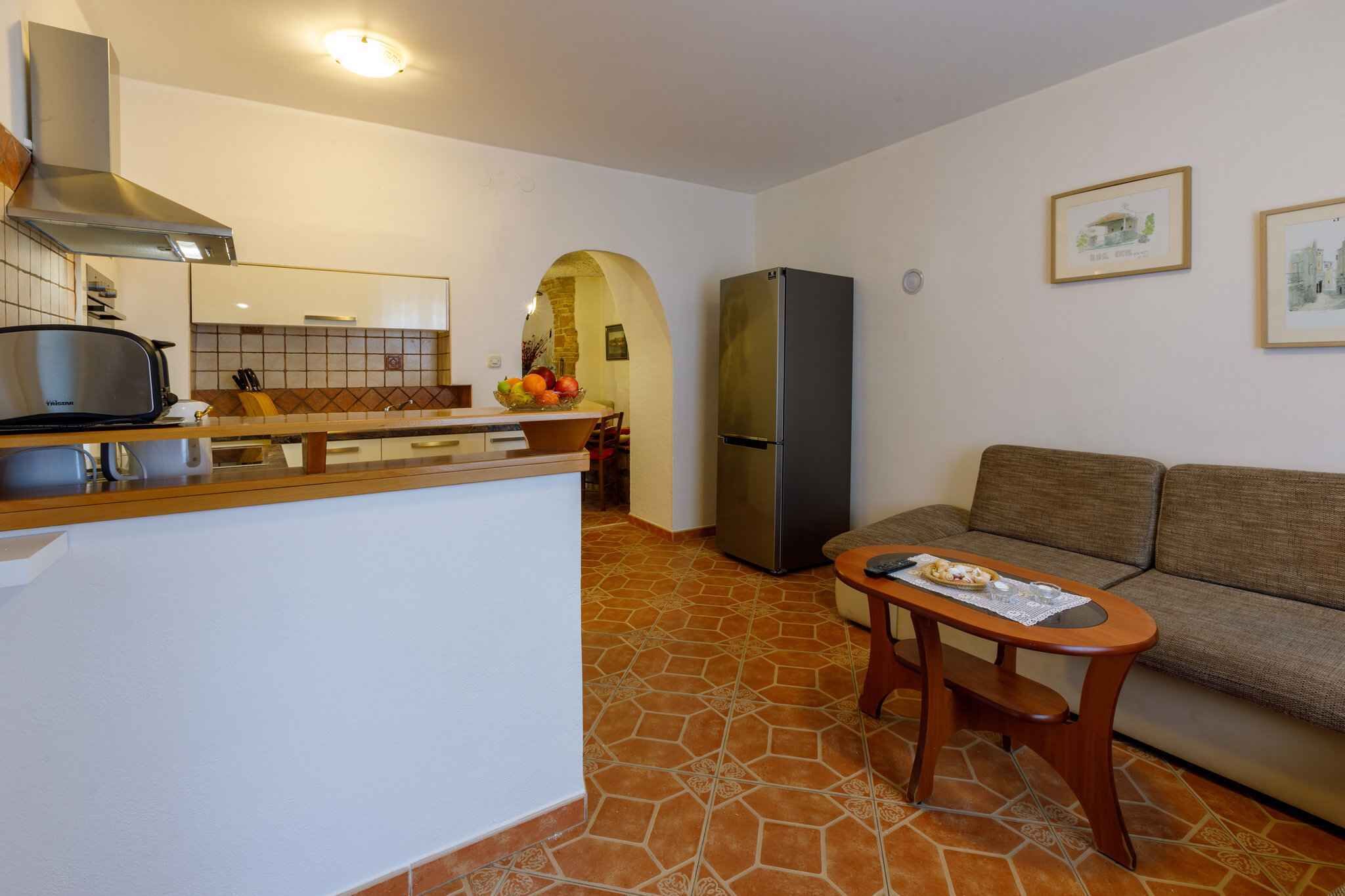 A compact living space with a kitchenette, a sofa, and a small table.