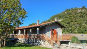 A two-story stone building with a red-tiled roof, a wooden balcony, and a staircase leading to the upper floor. - Beautiful  villa for 4 guests with WIFI, TV and pets allowed (Castelveccana)