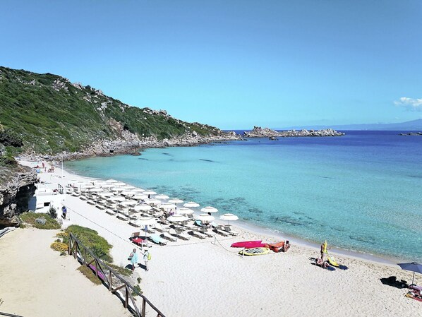 Enjoy sunbathing and swimming in this well-maintained beach area with calm waters and scenic rocky cliffs.