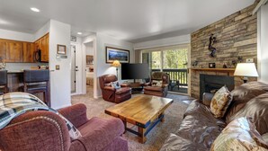 A living room with a fireplace, leather sofas, a wooden coffee table, and a stone wall. - Managed by Park City Lodging-True Ski-In/Ski-Out to Park City Mountain Resort! (Park City)