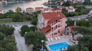 A multi-story building with a swimming pool, surrounded by greenery and a view of the sea. - Apartments Njirić - Family Studio with Balcony Sea View - No.2 (Zaton)