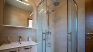 A modern bathroom with a glass-enclosed shower, a white sink, and a mirror above the sink. - Apartments Njirić - Family Studio with Balcony Sea View - No.2 (Zaton)