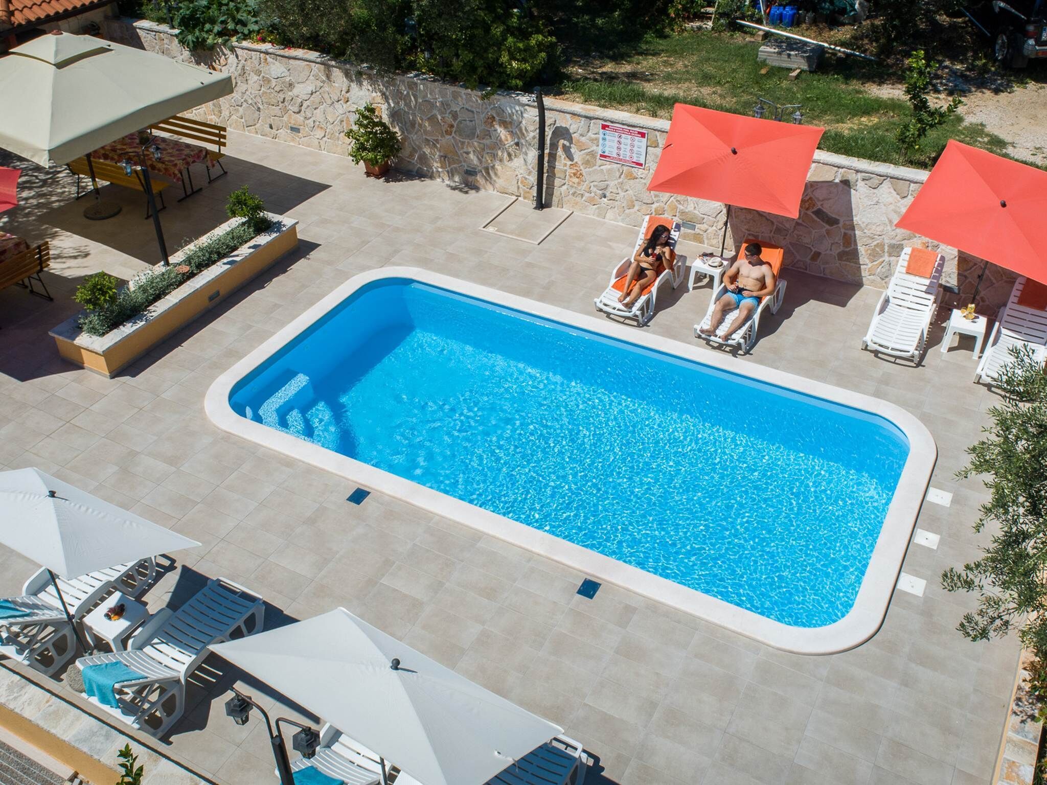 Una piscina rectangular rodeada de sillas de descanso y sombrillas.