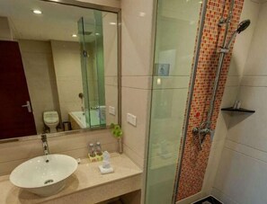 A bathroom with a glass-enclosed shower, a white sink, and a mirror above the sink.