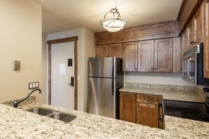 A kitchen with granite countertops, stainless steel appliances, wooden cabinets, and a built-in oven.