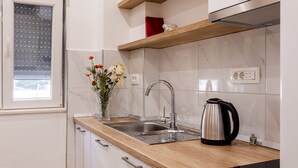 Una cocina moderna con un lavamanos de acero inoxidable, encimera de madera y un hervidor.