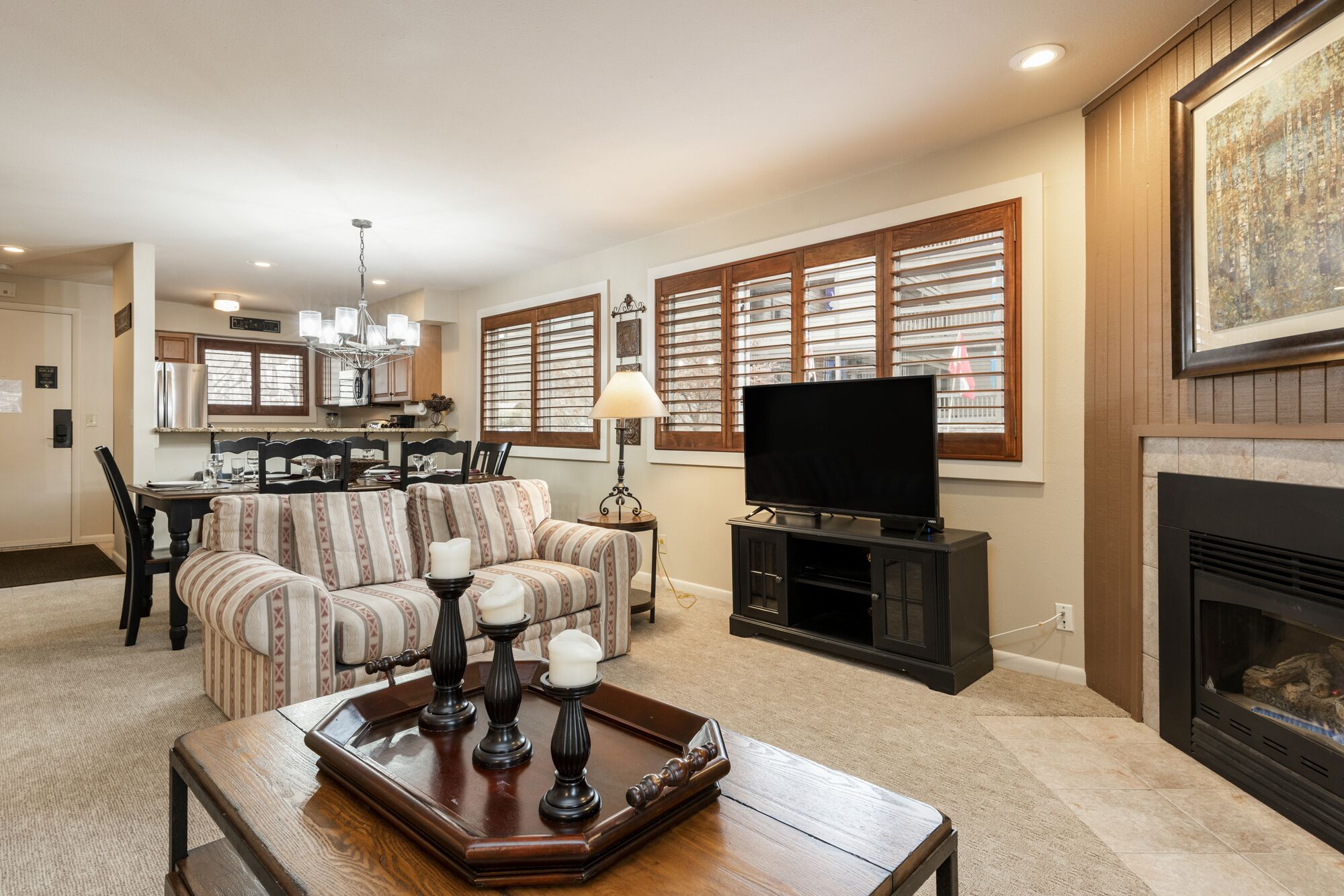 A living room with a sofa, a coffee table, a TV, and a fireplace.