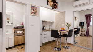 A modern kitchen with white cabinets, a wooden countertop, and a dining area with black chairs. - Apartments Martha-Superior Studio No.3 (Dubrovnik)