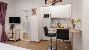 A modern kitchen with a microwave, refrigerator, and a wooden countertop. There is a black chair and a small shelf with a plant and a mug. - Apartments Martha-Superior Studio No.3 (Dubrovnik)
