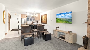 A modern living room with a dining area, a large TV mounted on the wall, and a fireplace. - Managed by Park City Lodging-True Ski-In/Ski-Out to Park City Mountain Resort! (Park City)