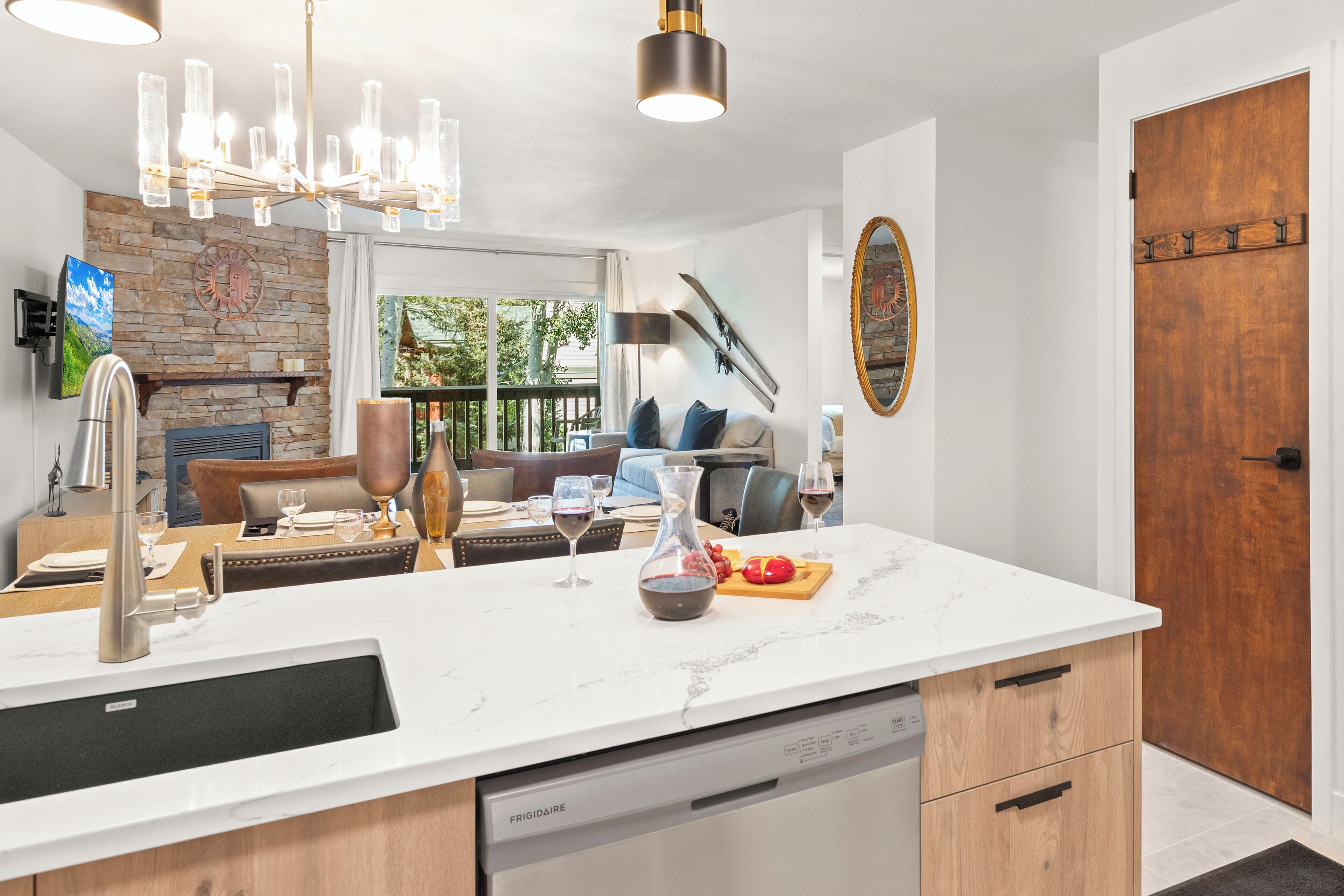 A modern kitchen with a marble countertop, stainless steel appliances, and a dining area with a view.