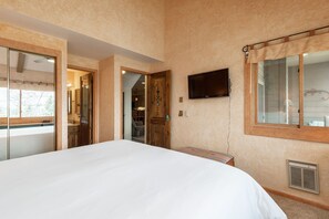 Una camera da letto con un letto grande, una televisione a parete e una finestra con tenda.