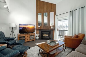 A modern living room with a fireplace, a television, and leather furniture.