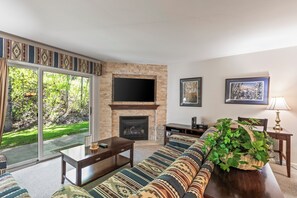 A living room with a fireplace, a sofa, a coffee table, and a TV mounted on the wall.