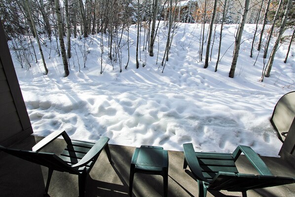 A view from a window overlooking a snowy forest with three green Adirondack chairs outside. - True Ski-In/Ski-Out to Park City Mountain Resort I Managed by Park City Lodging (Park City)