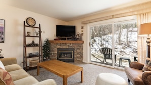 A cozy living room with a fireplace, a television, and a view of a snowy outdoor area. - Managed by Park City Lodging-True Ski-In/Ski-Out to Park City Mountain Resort! (Park City)