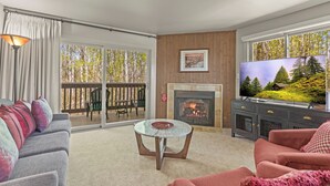 A living room with a fireplace, a television, and a balcony with outdoor furniture.