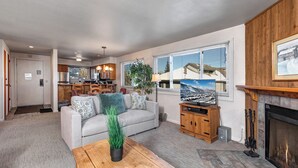A spacious living room with a fireplace, a dining area, and a kitchen.