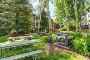 An outdoor patio area with picnic tables, a barbecue grill, and a sign indicating a family BBQ and picnic area. - Balcony Overlooking Slope|Hot Tub|Ski-In/Ski-Out|Managed by Park City Lodging (Park City)