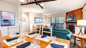 A dining area with a wooden table set for four, a fireplace, and a cozy seating area with a green sofa. - Managed by Park City Lodging-True Ski-In/Ski-Out to Park City Mountain Resort! (Park City)