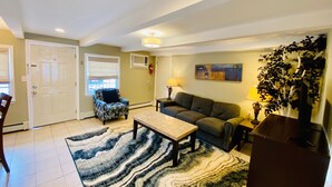A living room with a sofa, armchair, coffee table, and patterned rug.