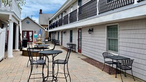 A courtyard with outdoor seating, a fountain, and a building with a balcony.
