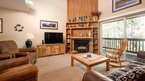 A living room with a fireplace, wooden shelves, a television, and a view of the outdoors. - True Ski-In/Ski-Out to Park City Mountain Resort I Managed by Park City Lodging (Park City)