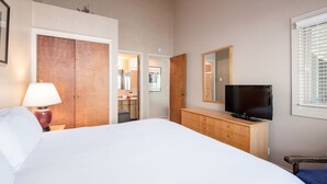 A hotel room with a large bed, a wooden dresser with a TV, a mirror, and a door leading to a bathroom. - True Ski-In/Ski-Out to Park City Mountain Resort I Managed by Park City Lodging (Park City)