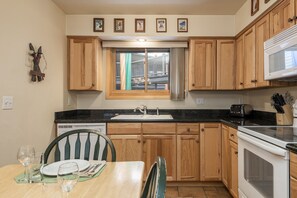 Enjoy cooking in this fully equipped kitchen with a sink, stove, and toaster, and dine at the adjacent table with comfortable seating.