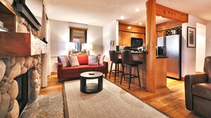 Una sala de estar acogedora con chimenea, un sofá rojo y una cocina con armarios de madera y electrodomésticos modernos.