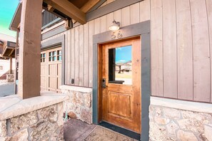 A wooden building with a stone foundation, a wooden door, and a number '56' above the door.