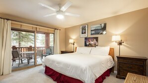 Une chambre d’hôtel avec un grand lit, un ventilateur de plafond, un balcon avec des sièges d’extérieur et deux lampes fixées au mur.
