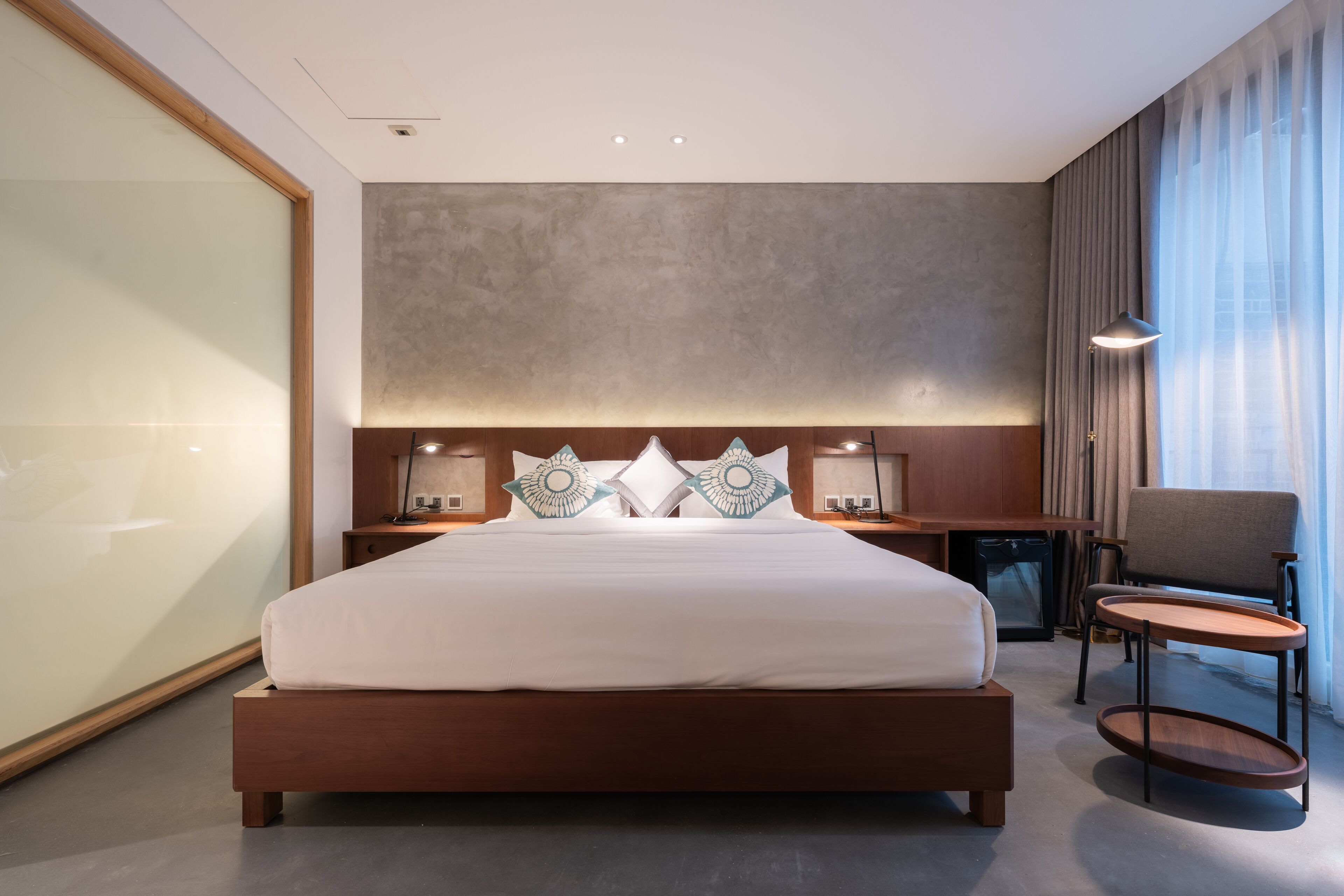 Une chambre d’hôtel moderne avec un grand lit, des tables de chevet, une chaise et un bureau.