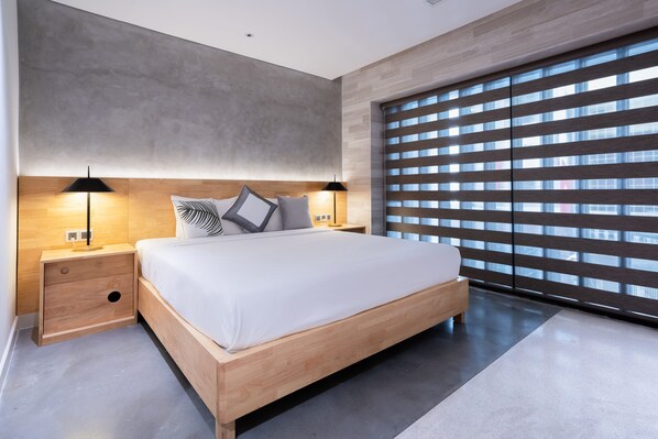 Een moderne slaapkamer met een groot bed, een houten hoofdbord, nachtlampjes en een uitzicht door het plafondhoge raam.