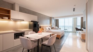 Een moderne hotelkamer met kitchenette, eethoek, bed en televisie.