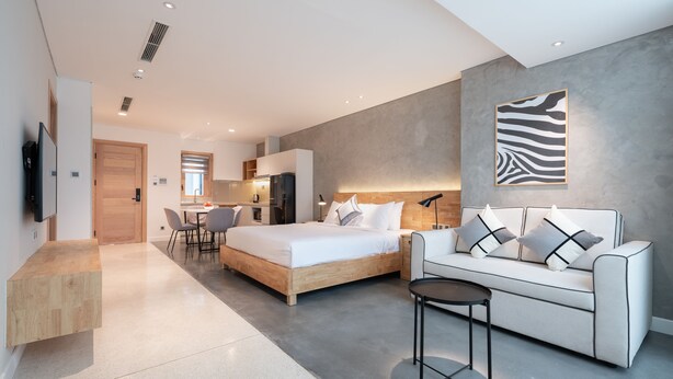 Een moderne hotelkamer met een bed, een slaapbank, een eethoek en een keuken.