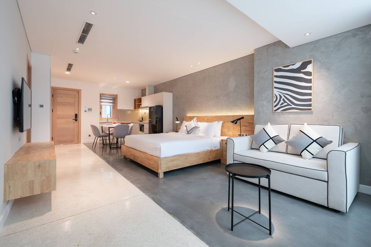 Een moderne hotelkamer met een bed, een slaapbank, een eethoek en een keuken.