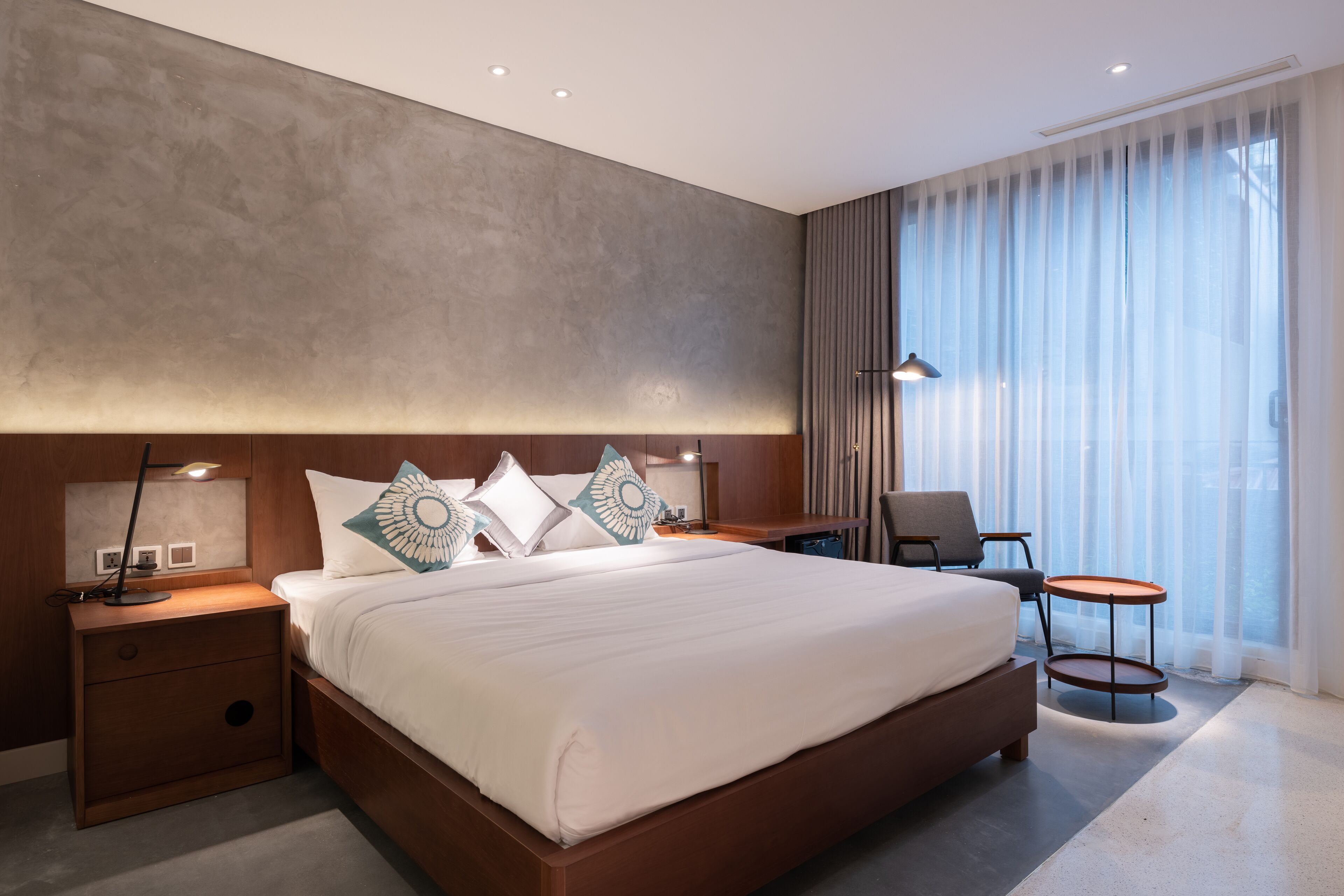 Une chambre d’hôtel moderne avec un grand lit, des tables de chevet, un bureau et une chaise.