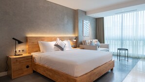 Een moderne slaapkamer met een groot bed, nachtkastjes, een bureau en een stoel.