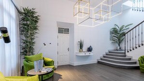 En moderne stue med grønne sofaer, et sofabord og en trappe, der fører op til en etage.