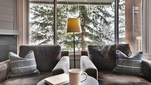 Ein gemütlicher Sitzbereich mit einer Couch, zwei Kissen, einem Tisch mit einer Tasse und einer Lampe.