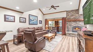 A living room with a stone fireplace, leather sofa, and a flat-screen TV. - Managed by Park City Lodging-True Ski-In/Ski-Out to Park City Mountain Resort! (Park City)