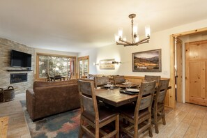A dining area with a wooden table and chairs, a fireplace, and a television mounted on the wall.