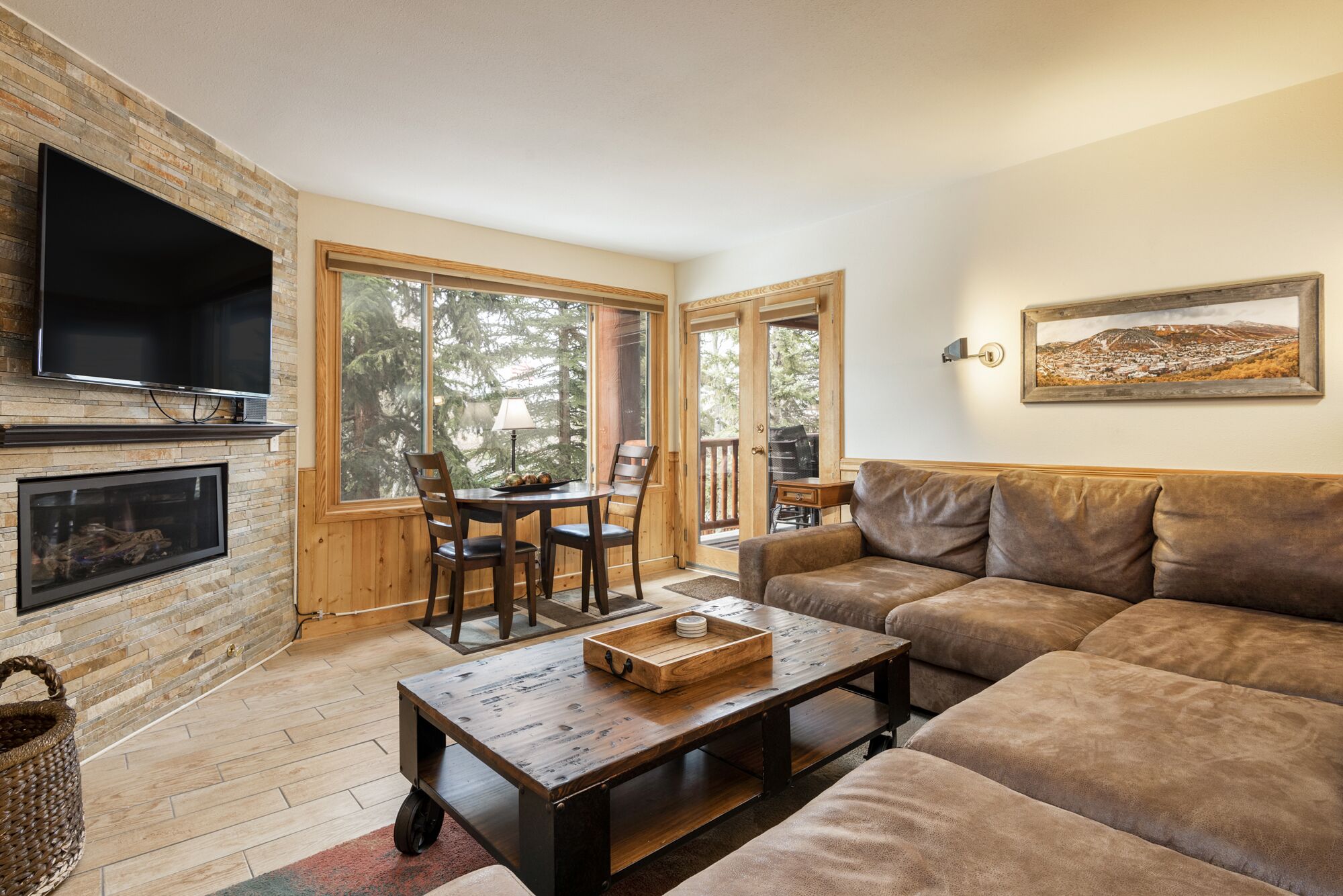A cozy living room with a fireplace, a television, a sofa, and a dining area with chairs.