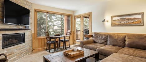 A cozy living room with a fireplace, a television, a sofa, and a dining area with chairs.