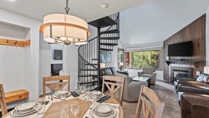 Ein modernes Interieur mit Essbereich, Wendeltreppe, Kamin und Ledersofas.